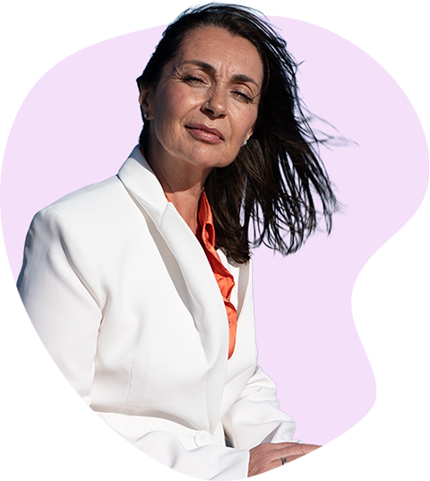Olga Hernández, con blazer blanco y blusa coral, sobre un fondo orgánico lila