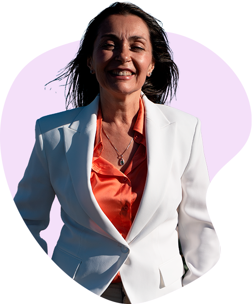 Olga Hernández sonriendo, con blazer blanco y camisa coral, sobre una forma lila